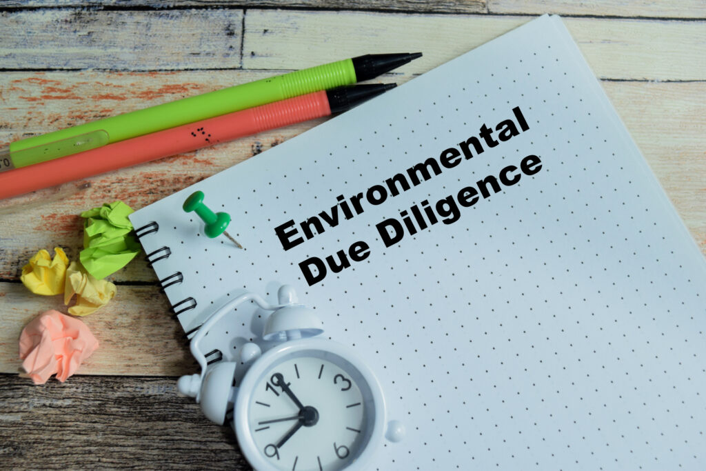 Bloco de notas com a inscrição Environmental Due Diligence sobre mesa de madeira