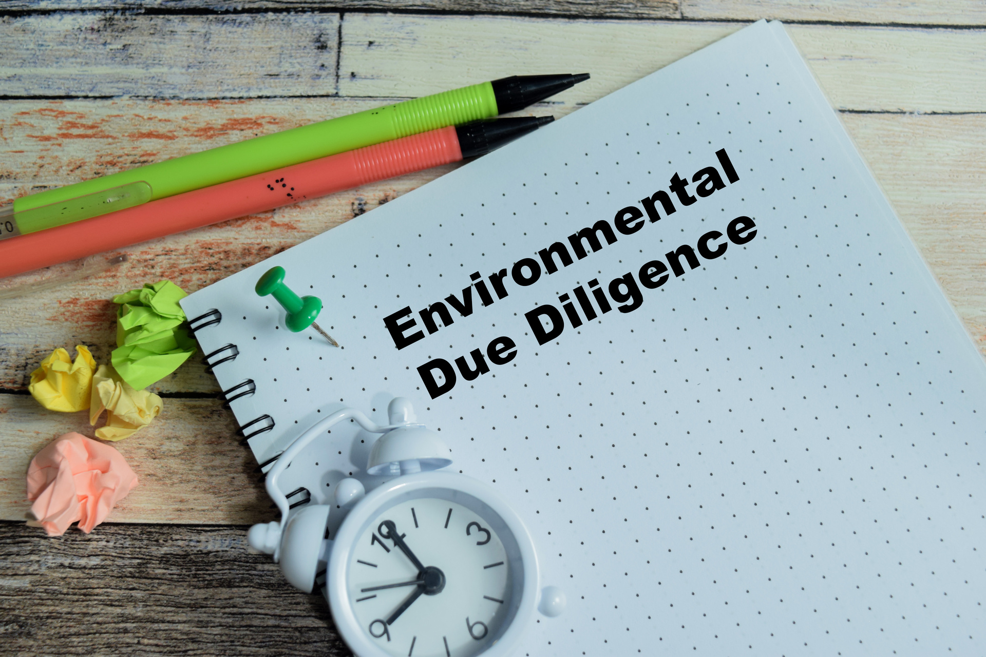 Bloco de notas com a inscrição Environmental Due Diligence sobre mesa de madeira